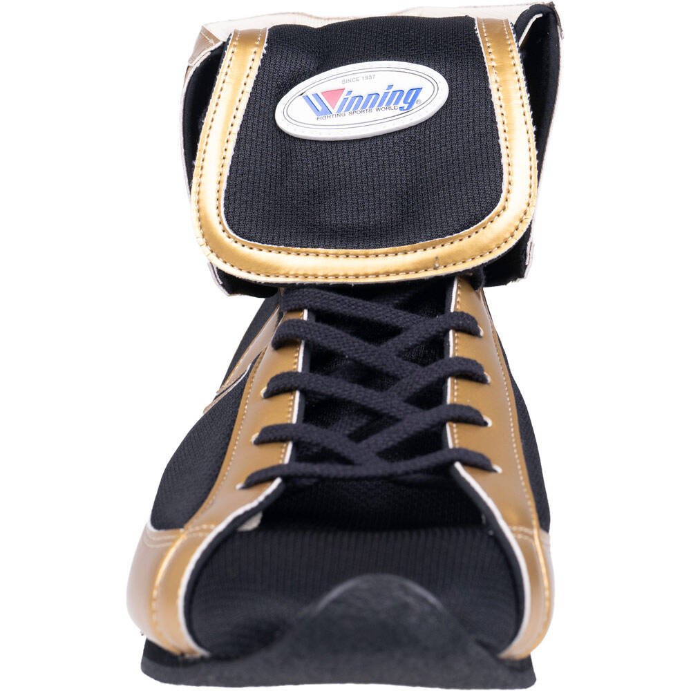 Close-up of Winning short-cut boxing boot showing black and gold fabric construction, laces, and oval Winning brand patch