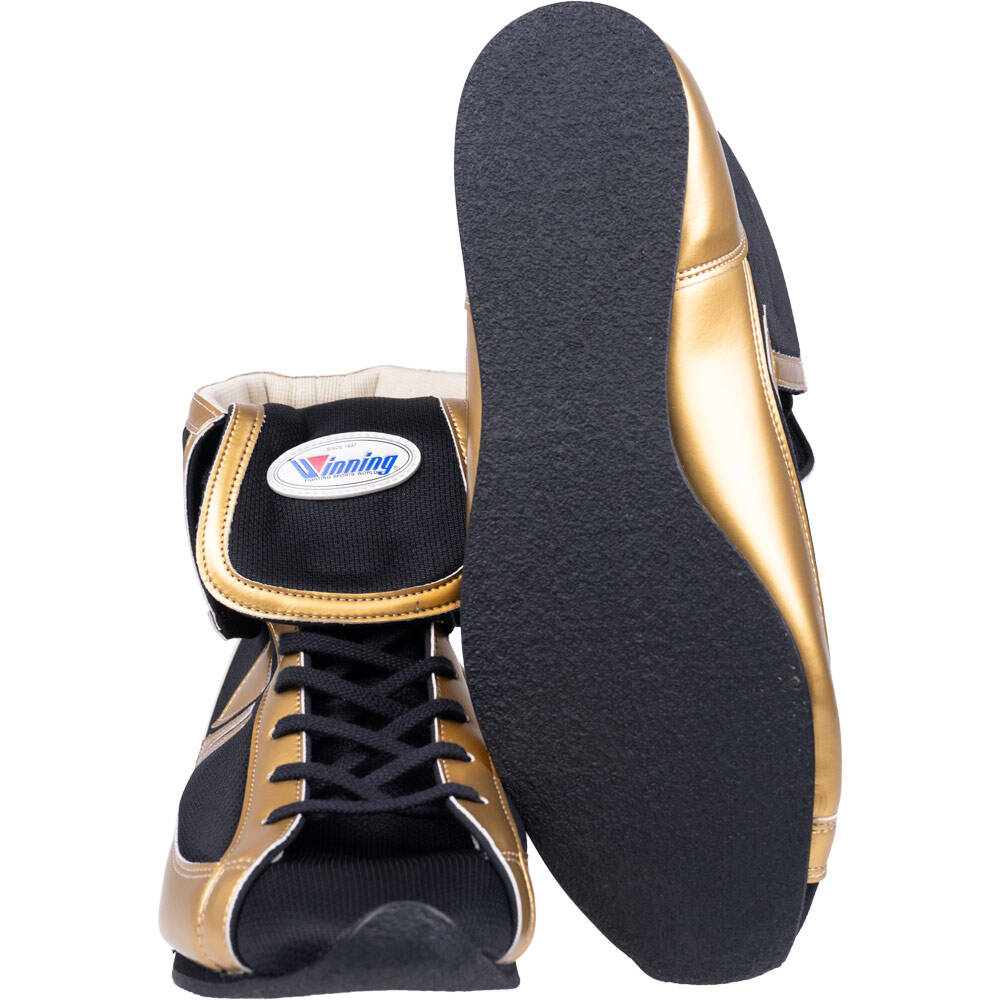 Winning short-cut boxing shoes in black and metallic gold showing side profile and textured black outsole